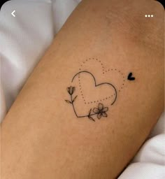 a small heart tattoo with flowers on the side of the arm and an arrow in the shape of a heart