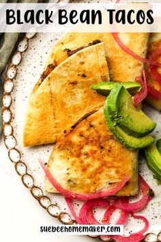 black bean tacos with avocado and sliced red onions on a white plate