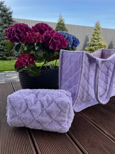 two purple towels sitting on top of a wooden table next to a potted plant