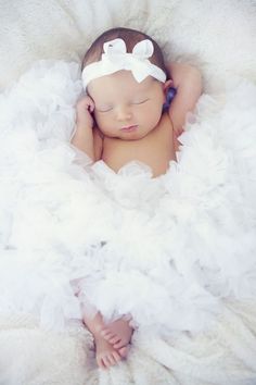 a baby is laying down wearing a white dress