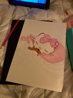 a drawing of a hello kitty laying on a bed next to a laptop computer and colored pencils