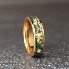 a gold ring with green and yellow flowers inlayed to the inside of it