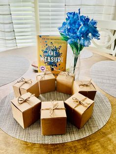 there are six boxes on the table with some blue flowers in front of them and a book