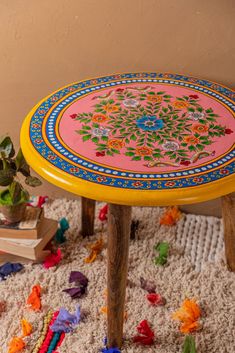 a colorful table sitting on top of a white rug next to a potted plant