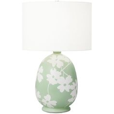 a green vase with white flowers on it and a white lamp next to it in front of a white background