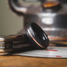 two wedding bands sitting on top of each other next to a metal container and some coins