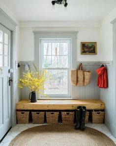 a wooden bench sitting in front of a window next to a basket filled with flowers