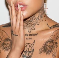 a woman with tattoos on her chest holding her hand up to her mouth