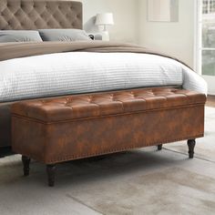 a bed with a tufted upholstered headboard and footstool in a bedroom