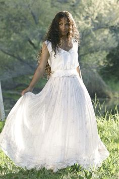 a woman wearing a white dress standing in the grass