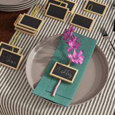 there is a place setting with flowers on the plate and small chalkboards attached to it