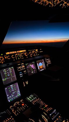 an airplane cockpit at night with the lights on and illuminated screens showing various aircraft's flight times