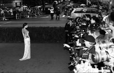 a black and white photo of a woman standing in front of a group of people