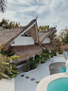 an outdoor swimming pool with thatched roof huts