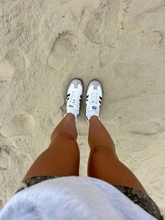 a person standing on top of a sandy beach next to the ocean with their feet in the sand