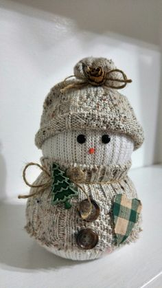 a knitted snowman sitting on top of a white shelf