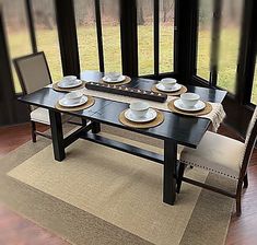 a table with plates and place settings on it in front of a large glass window