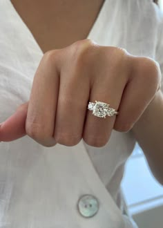 a woman's hand with a three stone ring on her finger, showing the middle finger