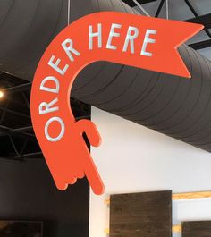 an orange sign that says order here hanging from the ceiling