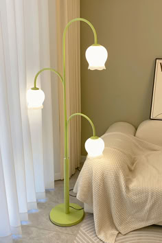 a green floor lamp sitting on top of a bed next to a white comforter