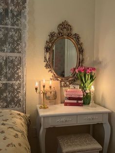 a bedroom with a bed, mirror and flowers on the dresser in front of it