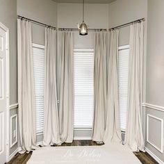 an empty room with white curtains and wood floors