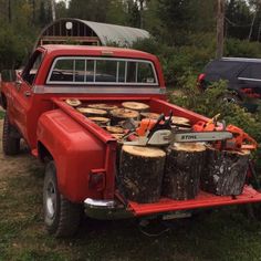 an old red pickup truck with logs in the bed and chains attached to the back