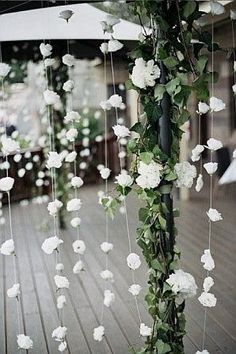 white flowers and greenery are hanging from a pole in the middle of a wooden floor