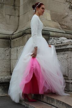 a woman in a white dress and pink skirt