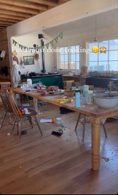 a messy kitchen and dining room with lots of clutter on the wooden flooring