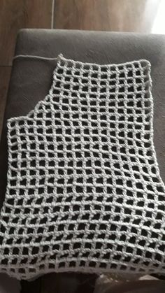 a white crocheted dishcloth sitting on top of a gray chair next to a wooden floor