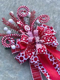 a red and white bow with candy canes on it's side, sitting on the ground