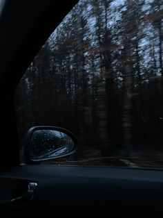 the rear view mirror of a car with trees in the background