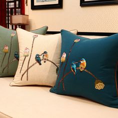 three pillows with birds on them sitting on a couch