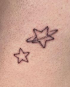 a small star tattoo on the back of a woman's neck, with two smaller stars behind it