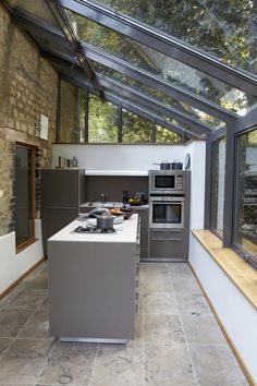 a kitchen with an oven, stove and sink in it's glass roof area