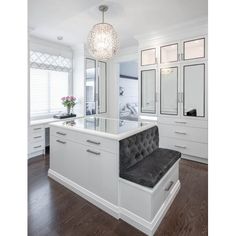 a large white bathroom with lots of mirrors and cabinets on the wall, along with a bench in front of it