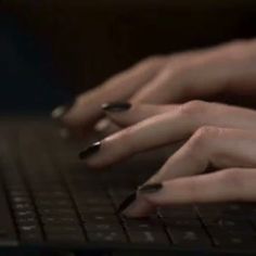 two hands typing on a laptop keyboard in the dark with their fingers resting on the keys