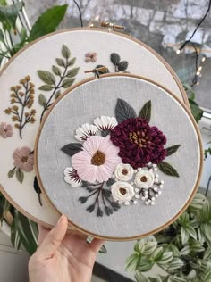 two embroidery hoops with flowers on them, one is pink and the other is white