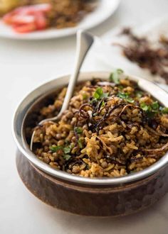 a bowl filled with rice and vegetables on top of a white table next to other plates