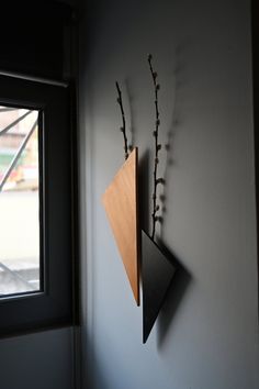 a clock mounted to the side of a wall next to a window with flowers in it