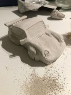 a car made out of clay sitting on top of a table next to other items