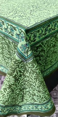 the table cloth is green and has an intricate design on it, while the rest of the table sits empty