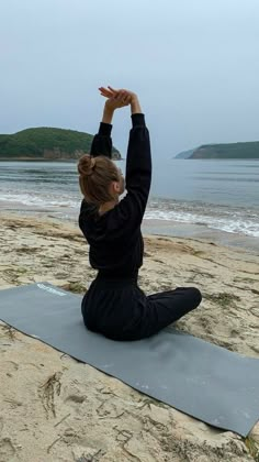 a woman is doing yoga on the beach