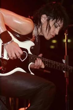 a man with black hair playing an electric guitar