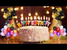 a birthday cake with lit candles surrounded by balloons