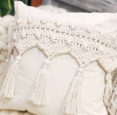 a crocheted pillow with tassels on it