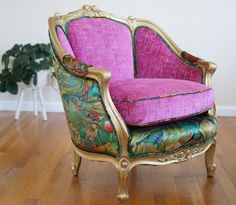 a pink and gold chair sitting on top of a hard wood floor next to a potted plant