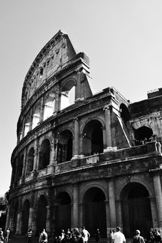 black and white photograph of people riding bikes in front of an old building