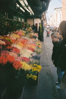 people are looking at flowers for sale on the street